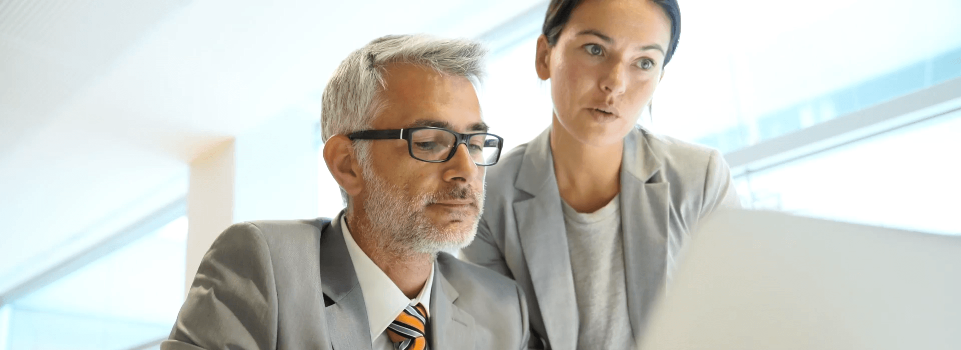 Concentrated team looks at office desk with laptop